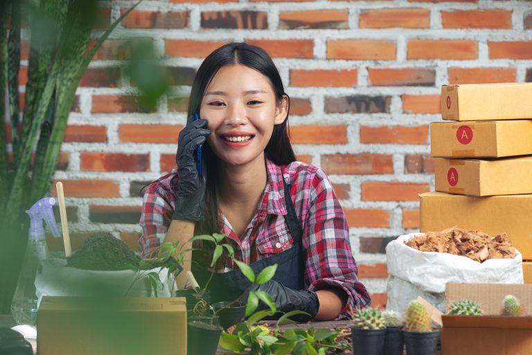 selling plant online;woman smiling while talking on cell phone