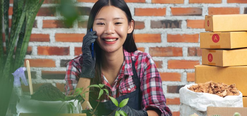 selling plant online;woman smiling while talking on cell phone